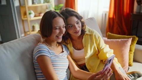 Smiling friends talking online looking in phone web camera on couch closeup. 스톡 동영상 333320583