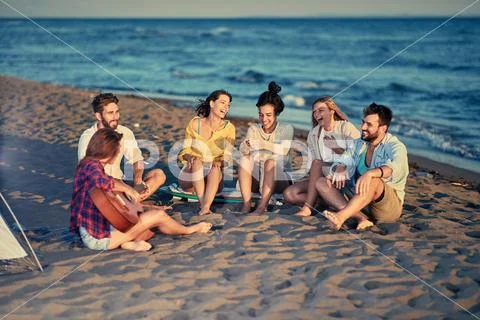 Smiling friends together relaxing with playing guitar and sing a song on sea Stock Photos