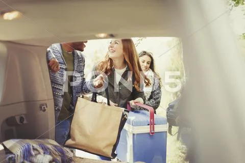 Smiling friends unloading back of car Stock Photos