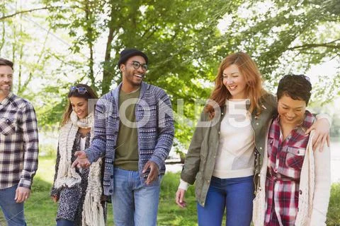 Smiling friends walking in park Stock Photos