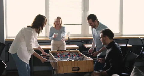 Smiling friends workmates playing table football together in office Stock Footage 221671296