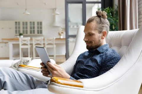 Smiling gadget user man reading book on tablet computer screen Stock Photos