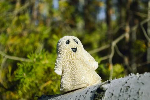 A smiling ghost toy close-up stands on a birch bark in the forest and sunlit Foto stock