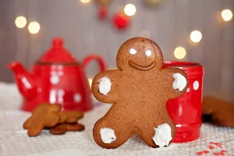 Smiling gingerbread man standing in front of a mug. teapot and more cookies o Stock Photos