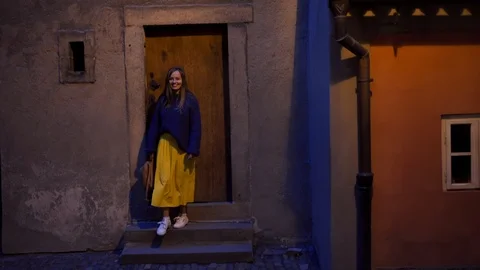Smiling girl with backpack in her hands descends stairs in lantern's warm light 스톡 동영상 115336997