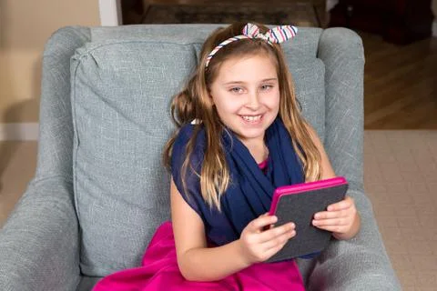 Smiling Girl in a Chair with a Tablet Stock Photos
