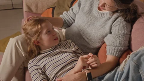 Smiling Girl Child Lying down on Couch Chatting with Mother at Home Stock Footage 334330677