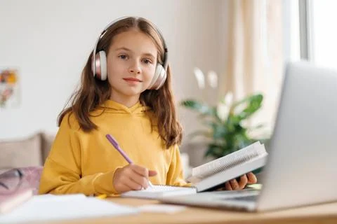 Smiling girl learning remotely using laptop and online tutor Stock Photos