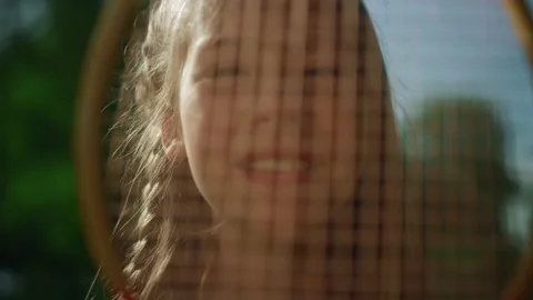 Smiling girl looking camera through racket net closeup. Pretty kid pose sunlight Stock Footage 170517475
