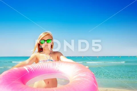 Smiling girl with pink swim ring on the beach Stock Photos