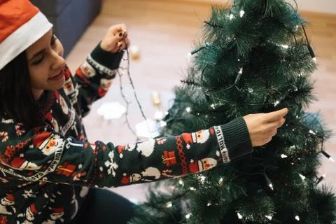 Smiling girl putting Christmas lights to tree Stock Photos
