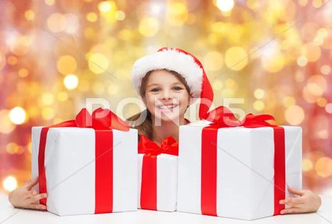 Smiling girl in santa hat with christmas gifts Stock Photos