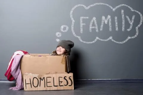 Smiling girl sitting in a paper box, sign Homeless Stock Photos
