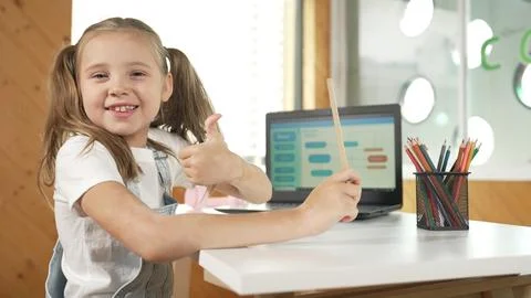 Smiling girl using laptop while look and show thumb up to camera. Erudition. Stock Photos