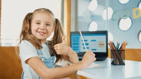 Smiling girl using laptop while look and show thumb up to camera. Erudition. Stock Photos
