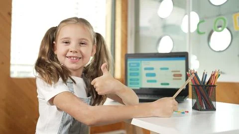 Smiling girl using laptop while look and show thumb up to camera. Erudition. Stock Photos