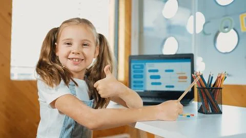 Smiling girl using laptop while look and show thumb up to camera. Erudition. Stockfoto's