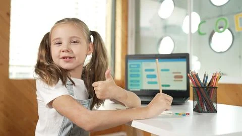 Smiling girl using laptop while look and show thumb up to camera. Erudition. Stockfoto's