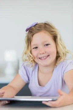 Smiling girl using tablet computer at table Stock Photos