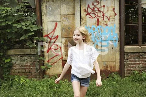 Smiling girl walking outside dilapidated building Stock Photos