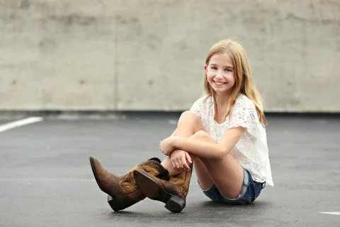 Smiling girl wearing cowboy boots in parking lot Stock Photos