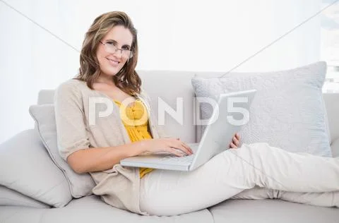 Smiling gorgeous model using laptop on cosy sofa Stock Photos