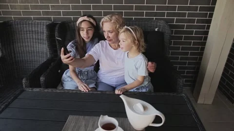 Smiling grandmother taking selfie with granddaughters on smart phone Stock Footage