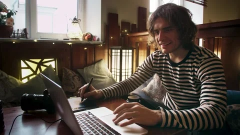 A smiling graphic designer draws on a graphics tablet and works remotely at a Stock-Footage 264067678