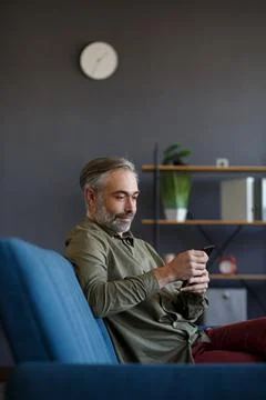 Smiling grey-haired man using mobile phone apps, texting message, browsing 스톡 사진