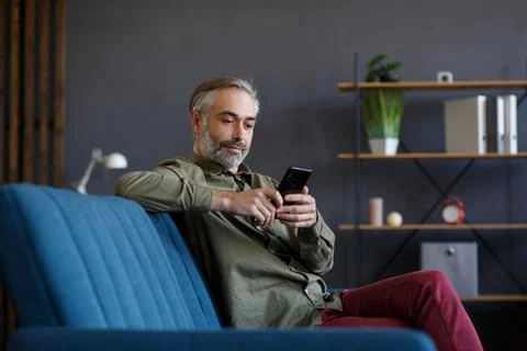 Smiling grey-haired man using mobile phone apps, texting message, browsing 스톡 사진