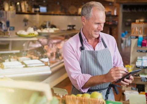 Smiling grocery worker checking inventory with digital tablet and stylus in Stock Photos