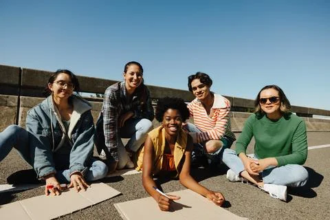 Smiling group of five activists sitting on the pavement during a peaceful d.. 写真素材