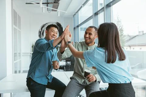 Smiling group of multiethnic colleagues drinking coffee and talking during break Stock Photos
