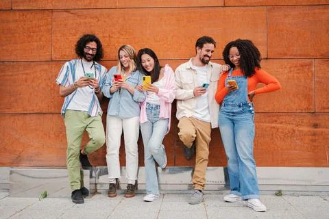 Smiling group of young friends using or watching their cellphone, sharing funny Stock Photos