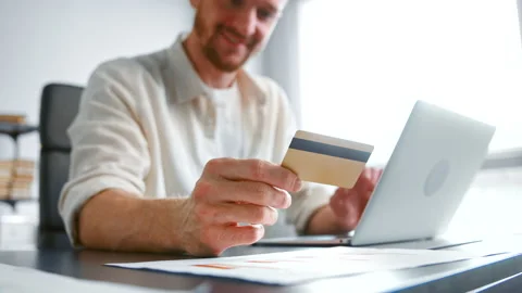 Smiling guy with beard pays company bills holding card Vidéo 155685489