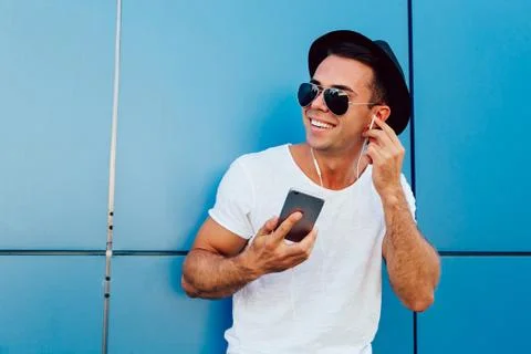 Smiling guy enjoying the music while listening in headphones, outdoors. Stock Photos