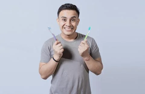 Smiling guy holding two toothbrushes isolated. Smiling people showing two t.. Stock Photos