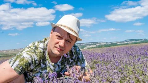 A smiling guy in a lilac box having a joyful face sits in a cap against a blue Stock Photos