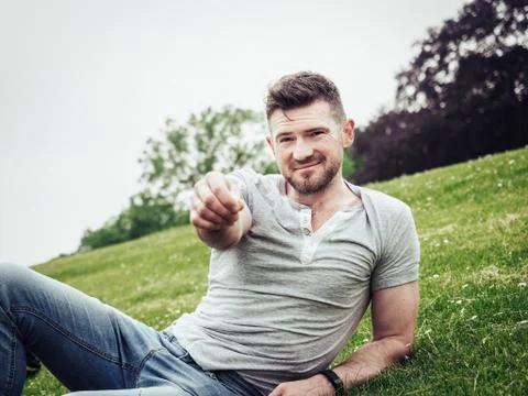 Smiling guy lying and relaxing on green grass Stock Photos