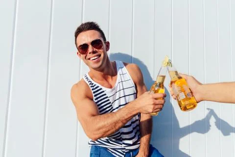 Smiling guy making a toast with bottle of beer, outdoors. Stock Photos
