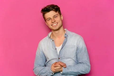 Smiling guy posing at camera on pink background. Stock Photos