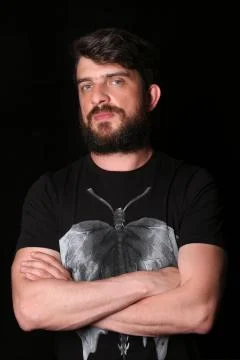 Smiling guy posing with crossed hands. Close.up. Black Stock Photos