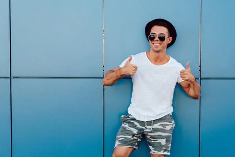 Smiling guy showing thumb up on two hands, standing outdoors Stock Photos