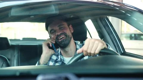 Smiling guy sitting in the car while talking on the smartphone. Transport Stock Photos