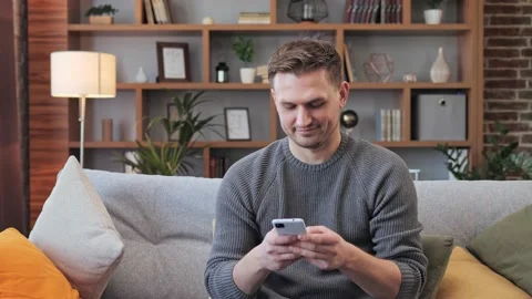 Smiling guy spend waste free time chatting surfing social media on mobile phone. Stock Footage 172393072
