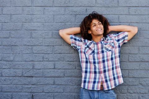 Smiling] guy standing against gray wall with hands behind head Stock Photos