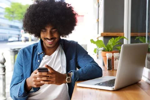 Smiling guy using mobile phone and laptop Stock Photos