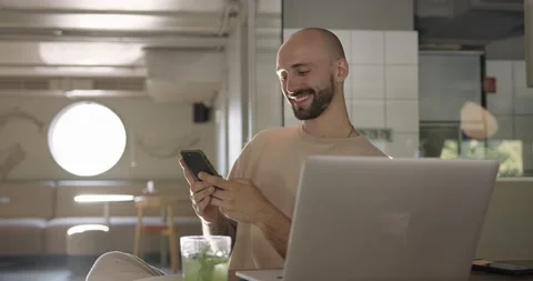 Smiling guy using smartphone and laptop at cafe Stock Footage 159082794