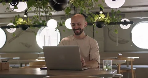 Smiling guy working on laptop at cozy cafe Stock Footage 159083548