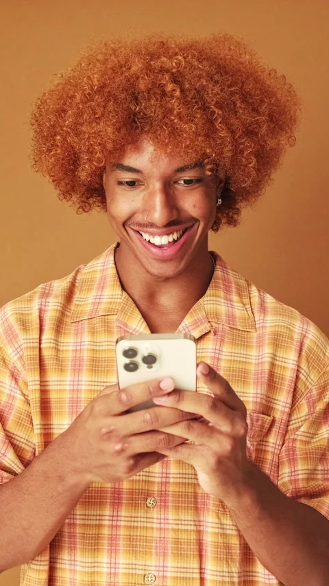 Smiling guy writing sms on mobile phone, isolated on brown background in studio Stock Footage 253933827